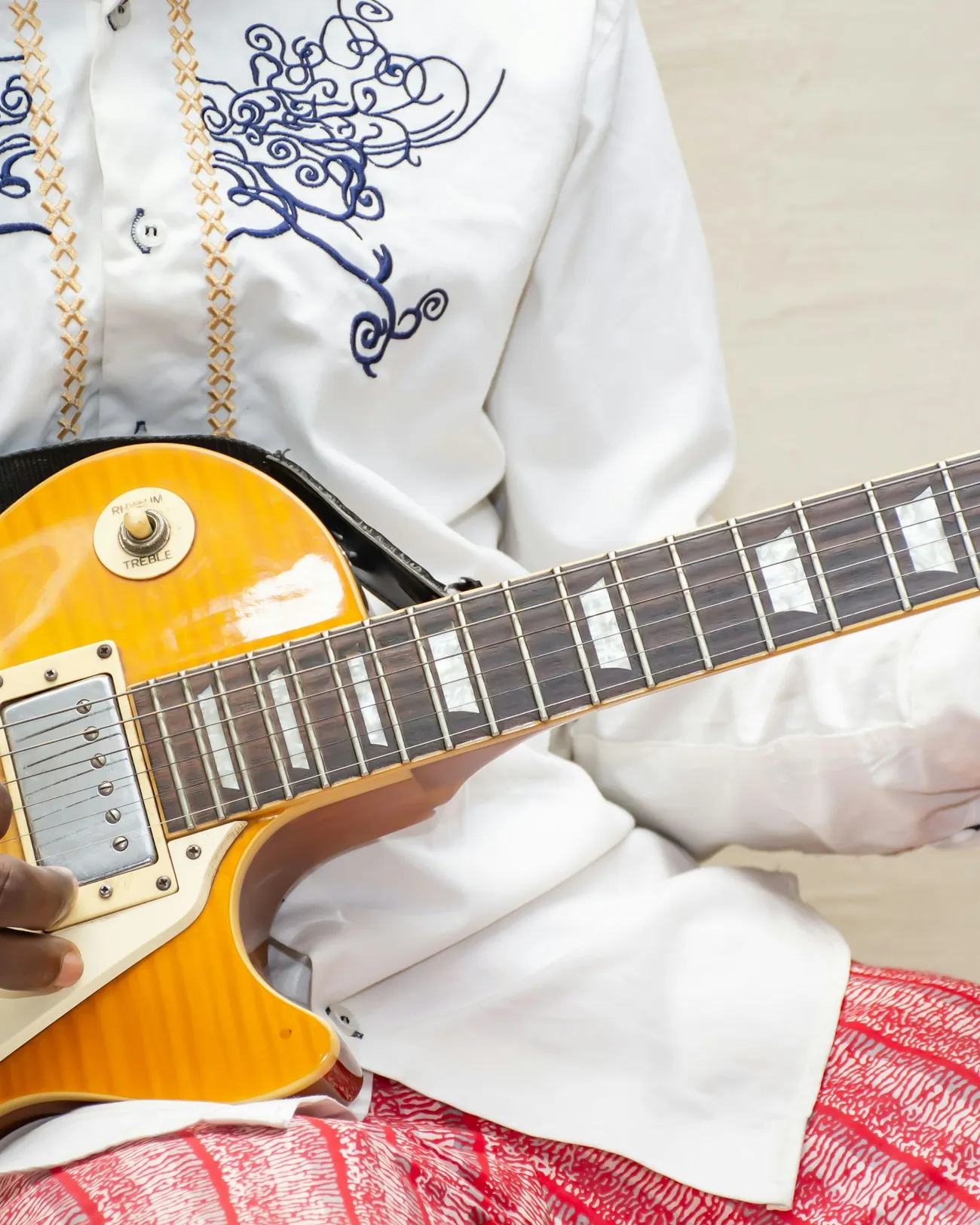 Close-up of hands playing a gold electric guitar