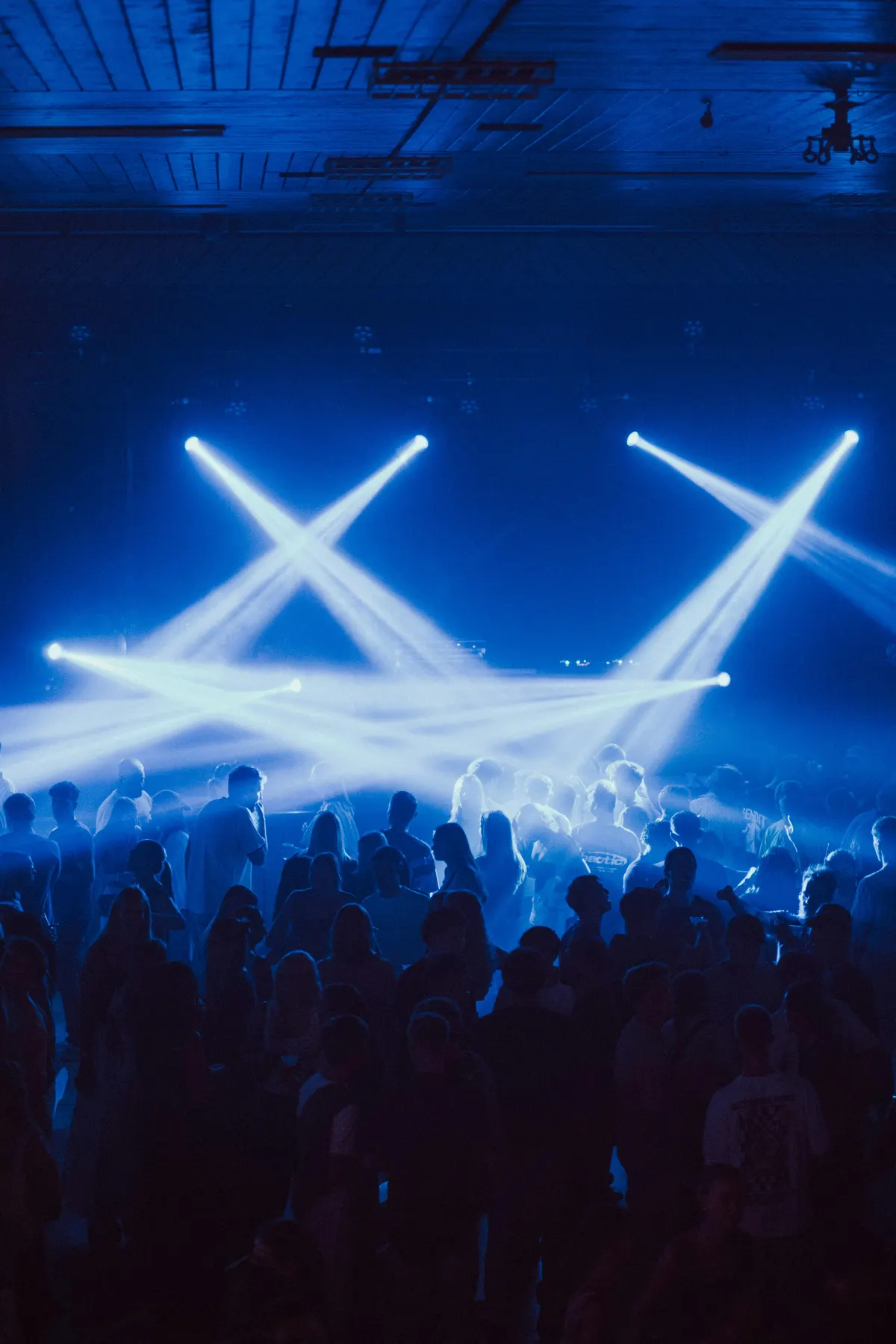 Blue stage lights sweeping over a concert crowd