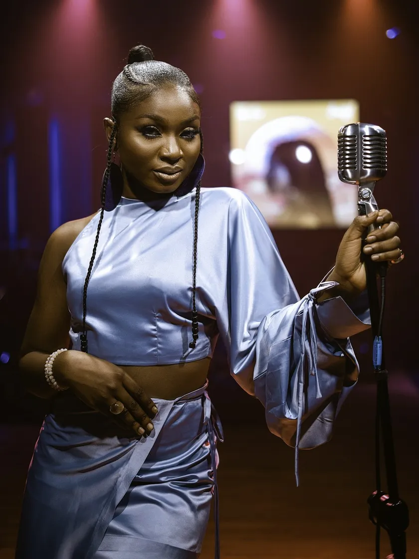A singer in silver standing at a microphone